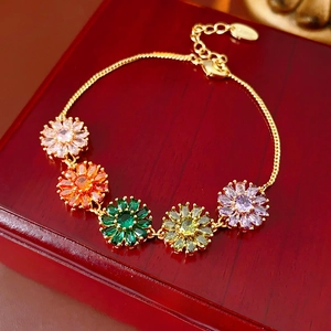 Macro shot of colorful zircon flower pendants on a gold chain over a wooden jewelry box