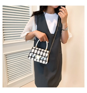 Détail du sac à bandoulière en tweed noir et blanc avec chaîne dorée et fermoir
