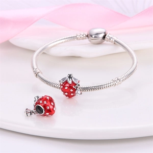 Detailed view of silver charm bracelet with red strawberry enamel beads and glossy finish