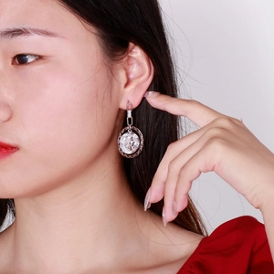 Detailed view of silver coin pendant earrings featuring vintage embossed portrait design