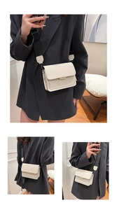 Close-up of cream square crossbody bag with wide black strap and matte leather finish