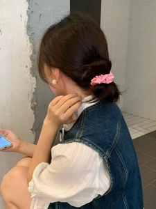 Close-up of a pink pleated cotton hair scrunchie worn by a model in a casual outfit