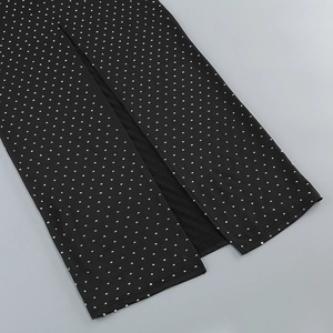 Detail of black dress hem featuring silver rhinestones and a stylish side slit design
