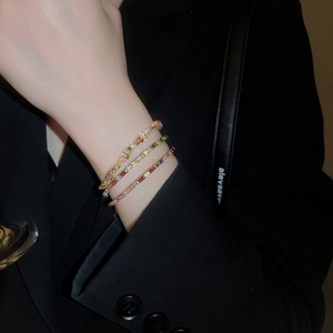 Close-up of three colorful gemstone bracelets stacked on a wrist with black background
