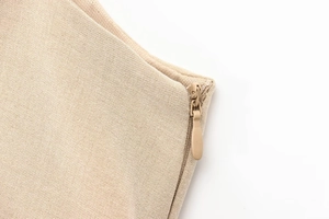 Dettaglio macro dell'abito beige a pieghe con cerniera invisibile e trama del tessuto fine