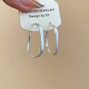 Detailed macro view of irregular matte silver hoop earrings with S925 sterling silver pins