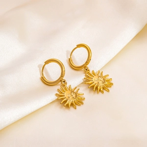 Macro detail of 18k gold plated hoop earrings with embossed sun face charm on white silk