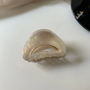 Detail view of the elegant pearlescent acetic acid hair claw with golden metal teeth