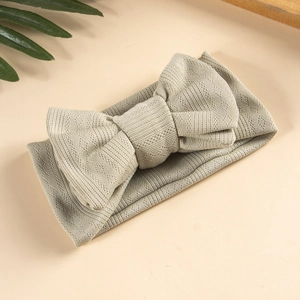Detail of high-stretch sage green jacquard knit baby headband with a large layered bow