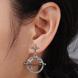 Close-up of star and planet earrings with pavé crystals in silver finish on ear