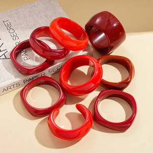 Retro red resin geometric bangles in round and C-shape styles on a minimalist background