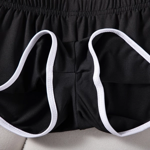 Detailaufnahme des elastischen Bunds und weißen Saums an schwarzen Yoga-Shorts