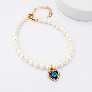 Detailed shot of pet pearl collar featuring a blue heart gemstone pendant with gold chain