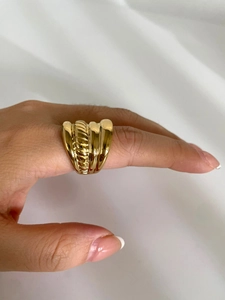 Macro shot of 18K gold plated croissant dome ring on finger over white satin