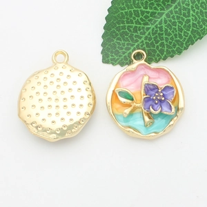 Close-up of golden alloy pendants with colorful enamel flowers and green leaves detail