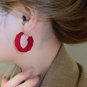 Detailed close-up of dark red fabric wrapped pleated hoop earring on a model