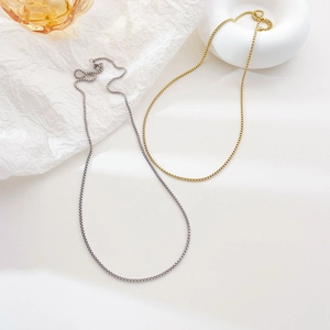 Elegant gold and silver box chain necklaces displayed on a minimalist white background