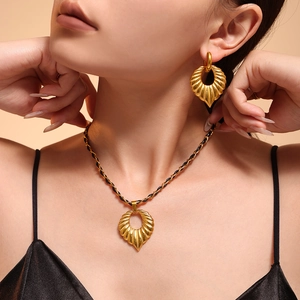 Golden shell jewelry set with necklace and earrings on model with black leather cord