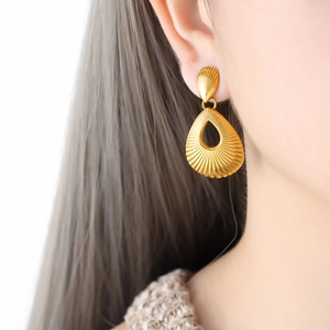 Golden teardrop hollow earrings with textured finish worn by a model for a stylish look