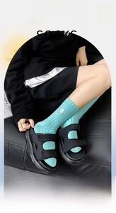 Détail de chaussettes en coton bleu sarcelle avec étiquette blanche et sandales noires
