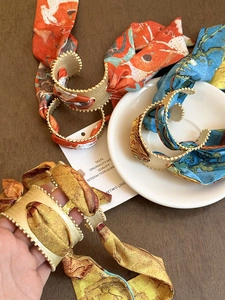 Detailed close-up of retro matte silk-textured headbands in orange, blue, and yellow hues