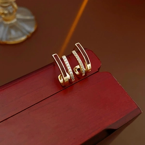 Détail de boucles d'oreilles C dorées avec émail rouge et zircons brillants sur une boîte