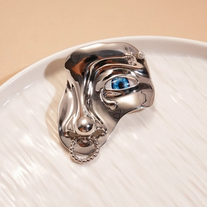 Gros plan de la broche visage surréaliste en argent avec œil bleu et cristaux