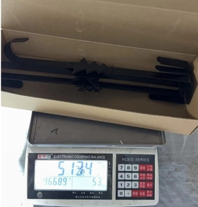 Detail view of black metal holiday wreath hangers being weighed on a scale for shipping