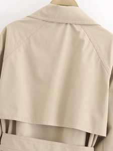Detailed back view of a beige trench coat featuring raglan sleeves and storm flap design