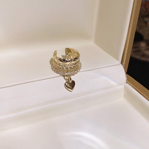 Detail of gold layered ear cuff with rhinestones and a hanging heart pendant