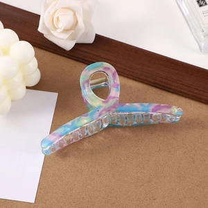 Detail of large acetate hair claw clip with blue and purple marble pattern on marble background