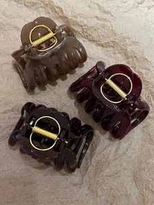 Detailed view of three acrylic pumpkin stripe claw clips in warm shades with gold springs