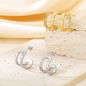 Close-up of gold and silver double C-shaped earrings with micro-set zircon stones