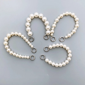 Detail view of five white gradient pearl beaded wrist straps with metal lobster clasps