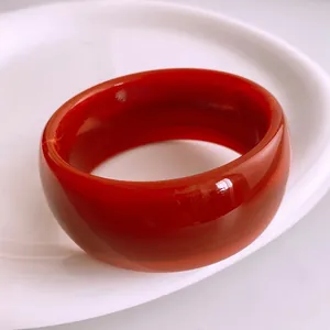 Bracelet jonc minimaliste en acrylique rouge à facettes sur un plateau en céramique