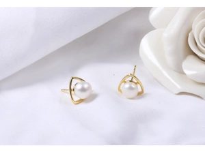 Detail view of natural freshwater pearl earrings in gold triangle frames on silk