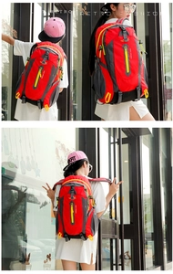 Close-up of red and grey outdoor backpack with yellow zipper pulls and mesh side pockets
