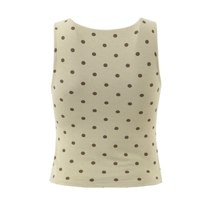 Détail du haut sans manches beige avec motif à pois marron sur un tissu fluide doux
