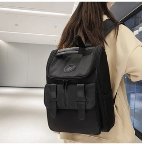 Detail view of the black nylon backpack showing top handle and buckle straps on the model