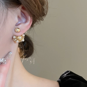 Close-up of vintage flower earrings with pearls and gold finish on female model