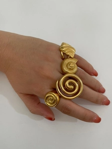 Detailed close-up of vintage golden spiral and conch-shaped rings on fingers