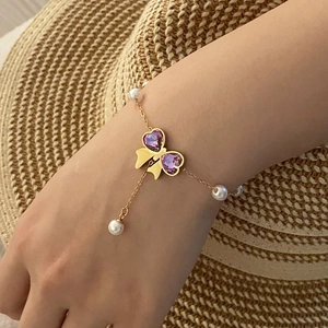 Golden bracelet featuring purple crystal butterfly and pearls on a model wrist