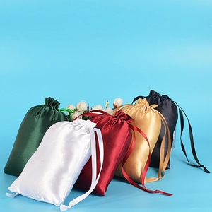 Still life of five silk drawstring pouches in green, white, red, gold and black