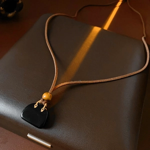 Detail of vintage leather cord necklace with black stone pendant and gold metal fastener