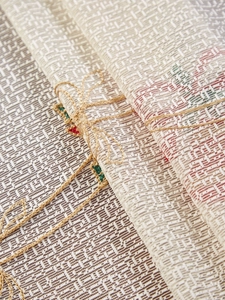 Detailed macro view of woven beige linen fabric with red and green geometric pattern detail