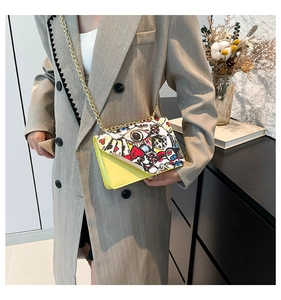 Detail of yellow crossbody bag with chain strap and graffiti print on female model