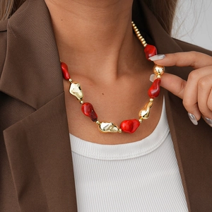 Close-up of red and gold irregular acrylic beaded sweater necklace worn by a fashion model