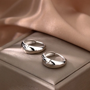 Pendientes de aro plateados minimalistas sobre seda champán para un estilo elegante