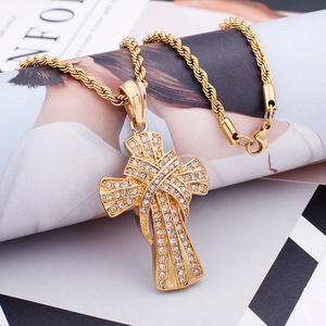Macro detail of a gold iced-out cross pendant and twist chain on a fashion magazine