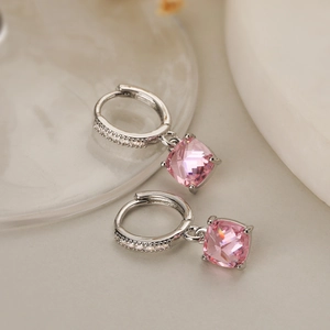 Macro detail of gold plated geometric earrings with pink cubic zirconia on marble